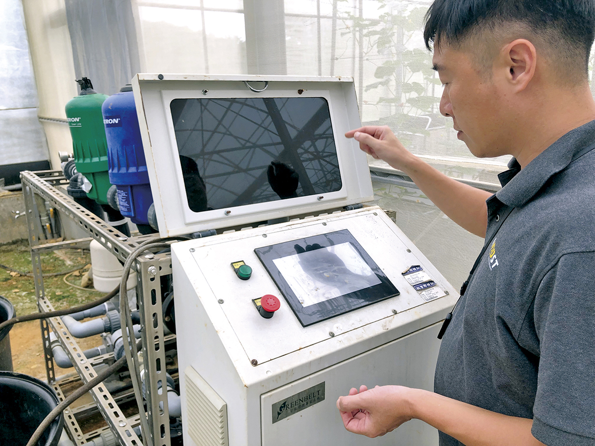 Professor Tsai Shang-han operates an integrated smart-farming console that links sensors and automated controls, enabling precise, real-time crop management. (Photo by Krakias Kai)