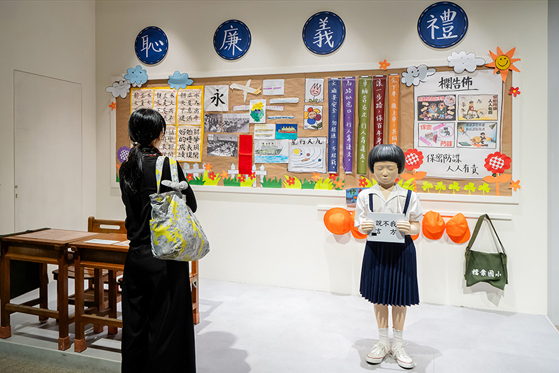A recreated 1980s classroom scene depicts a student being shamed under martial law era policies to enforce the use of Mandarin.