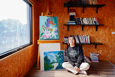 Lai sits beside her oil paintings in a bright, welcoming space where her children study and guests often read. (Photo by Chin Hung-hao)