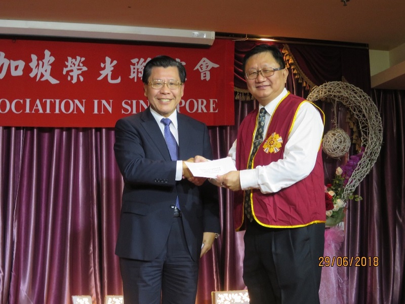 駐新加坡台北代表處梁代表國新(左)轉頒行政院退除役官兵輔導委員會核撥榮光會辦理活動經費補助款，由該會柯理事長昭群接受。