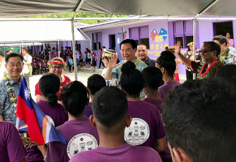 吳部長伉儷與馬國Ajeltake小學生揮手招呼,身後即是敦睦艦隊所繪製臺馬兩國建交20週年「邦誼永固」圖案
