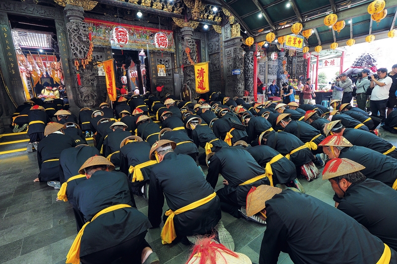 Sedan bearers bow down to their deity.