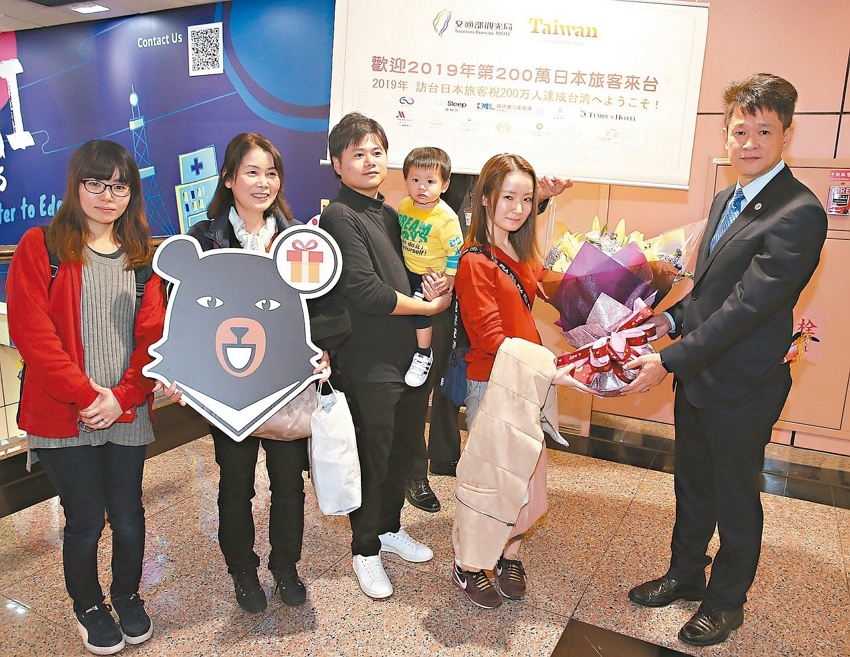 Huang Shih-fang (right), head of the Tourism Bureau’s International Affairs Division, welcomes the two millionth Japanese visitor (second right) to Taiwan Dec. 9 last year at Taoyuan International Airport, highlighting a record-setting year for inbound international tourism. (UDN)