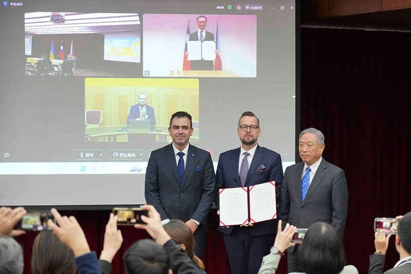 兩位簽署人持約本與見證人合影。