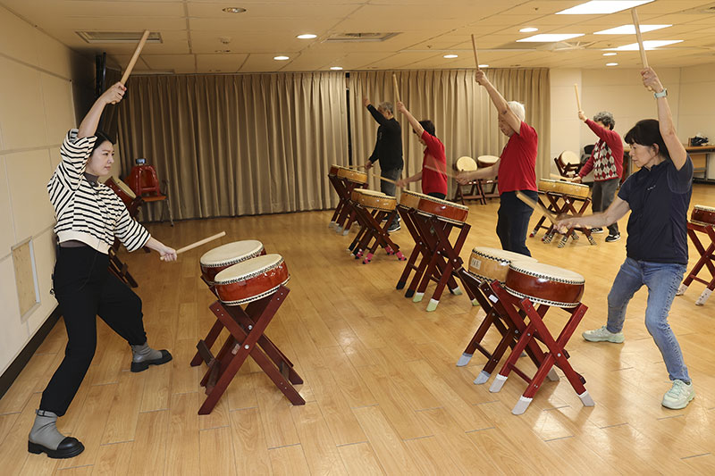 Residents of the Chang Gung Health and Culture Village put their all into pounding the drums in this taiko class, and leave the session filled with energy. (photo by Jimmy Lin)