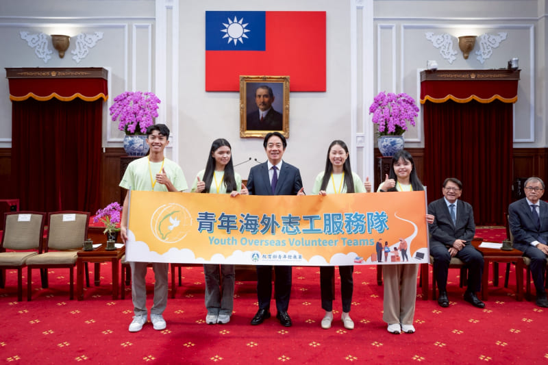 President Lai Ching-te (center) and the country’s youth volunteers set for overseas missions hold a poster at the Presidential Office June 17 in Taipei City. (Courtesy of PO)